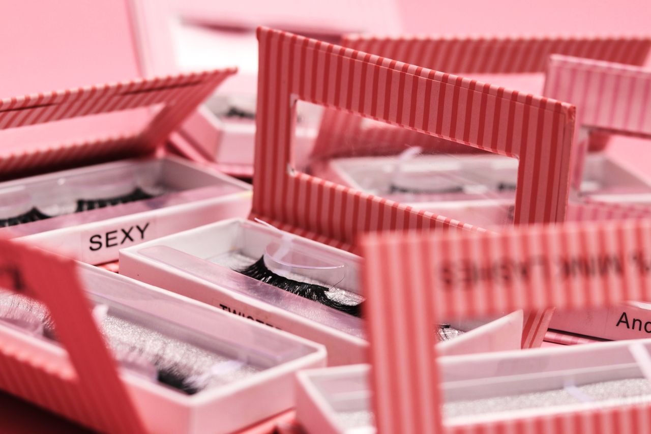 Delicate synthetic eyelashes in colorful striped packaging, perfect for cosmetics advertising.